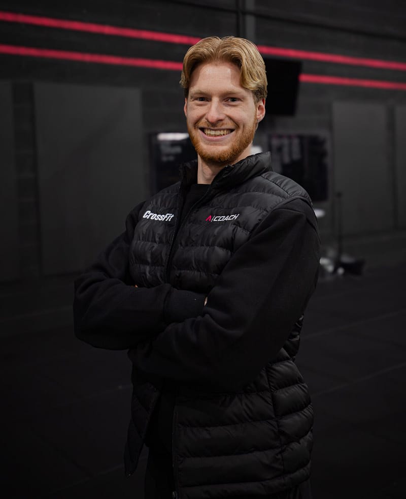 Smiling CrossFit coach standing inside modern gym