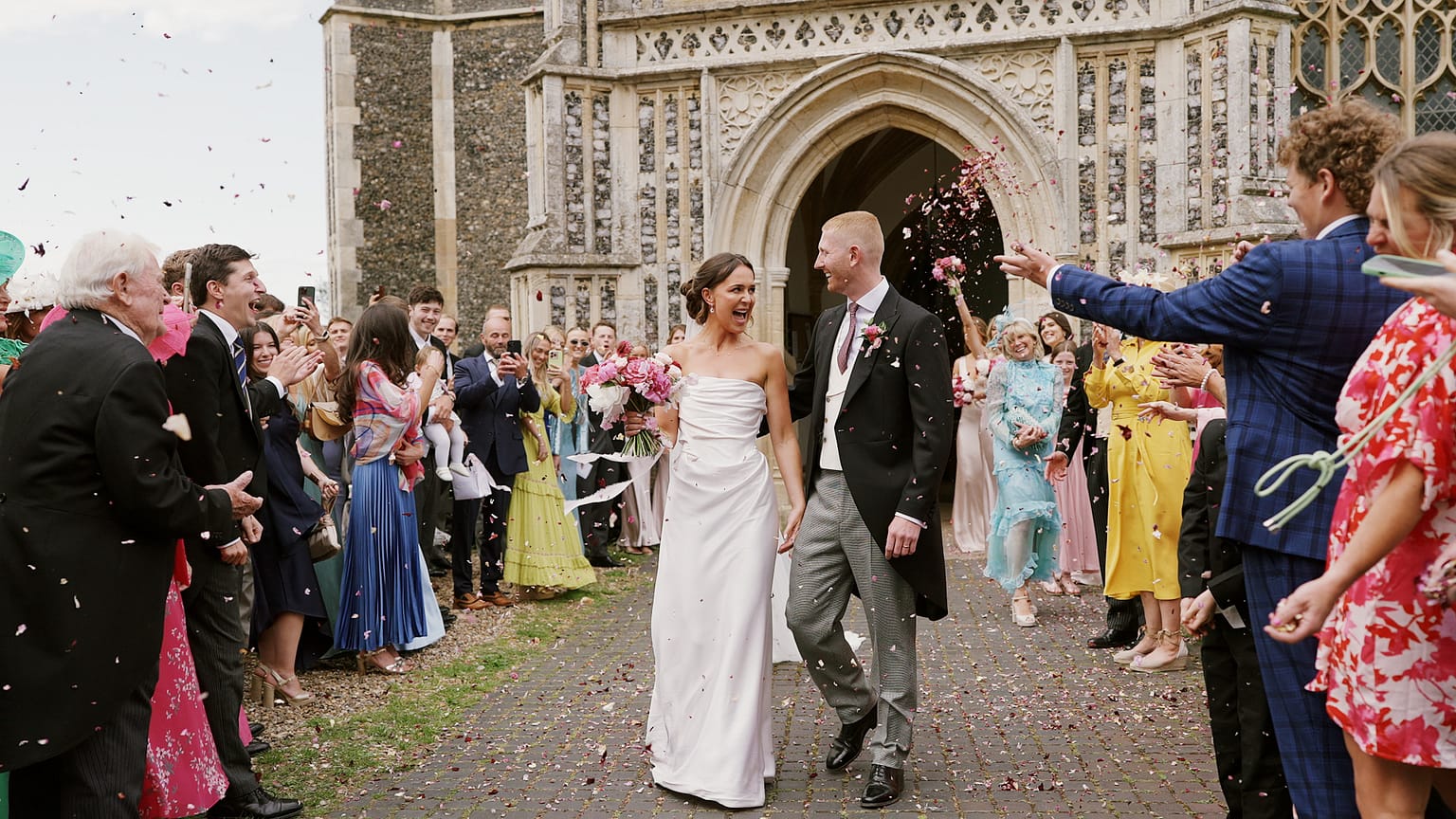 Newlyweds exit church amid confetti celebration.