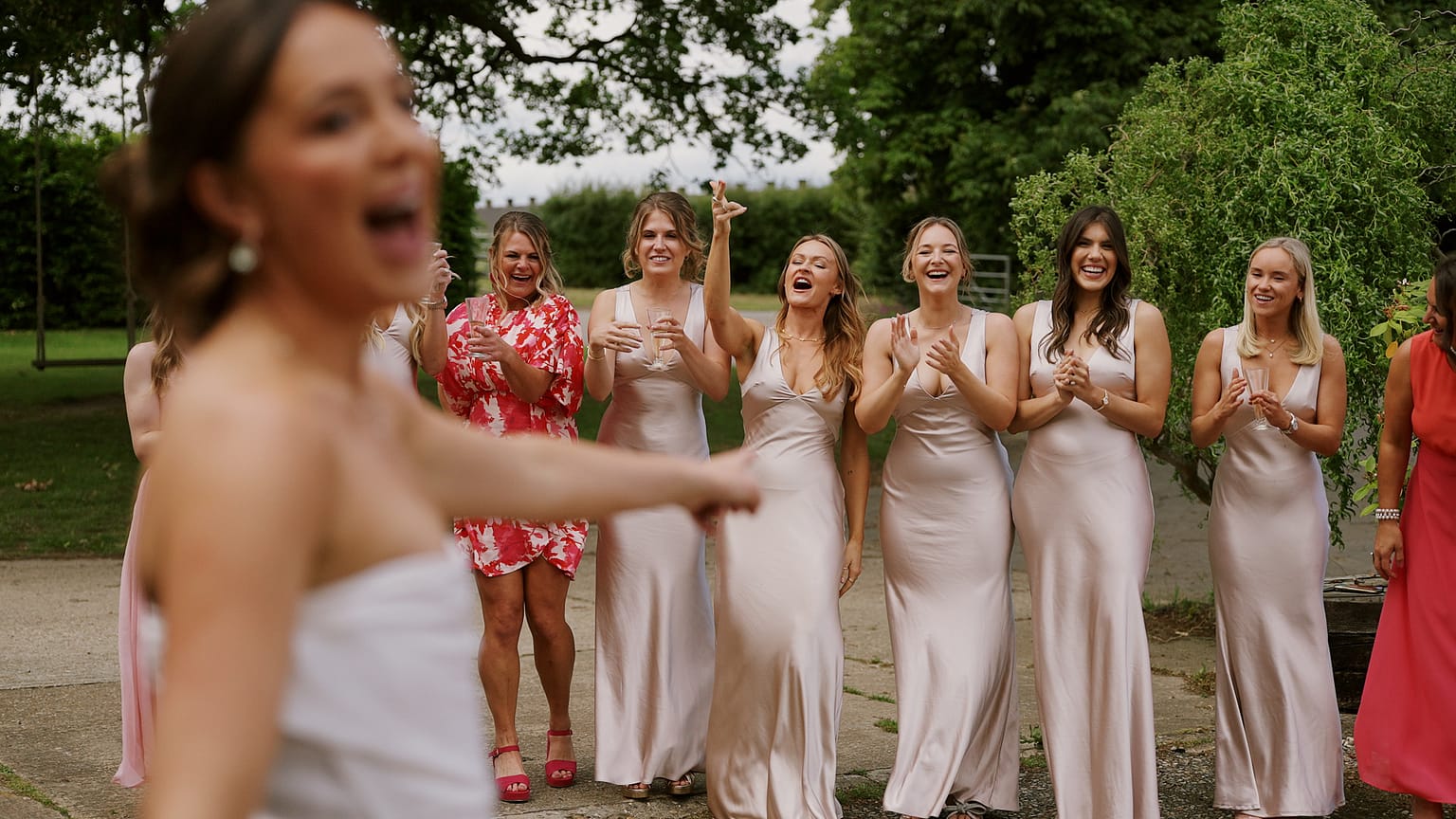 Bridesmaids cheering outdoors during wedding celebration.