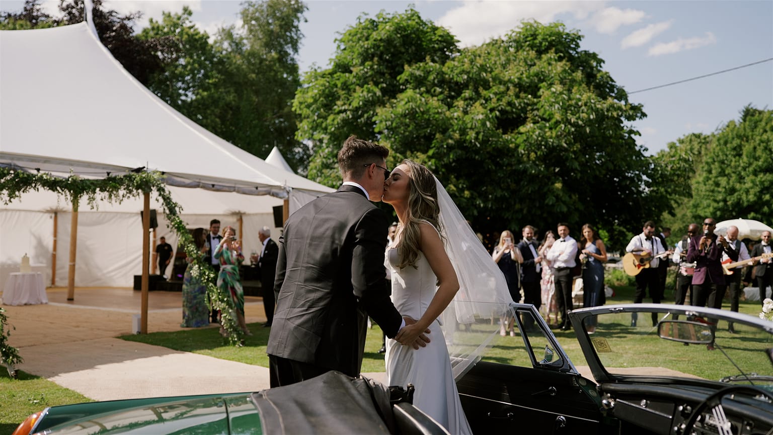 Bride and groom kissing at outdoor wedding celebration.