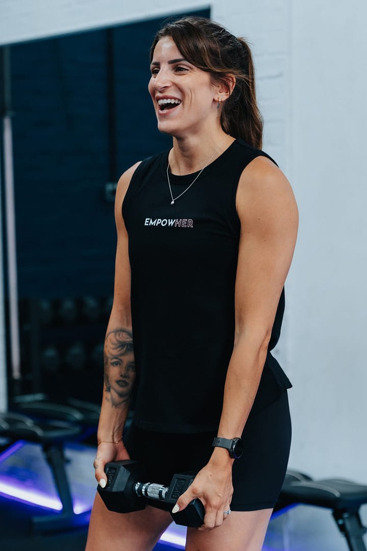 Smiling woman lifting dumbbells in gym workout