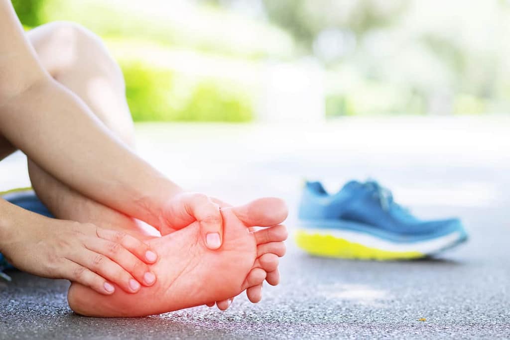 Runner with peripheral neuropathy in feet touching their foot