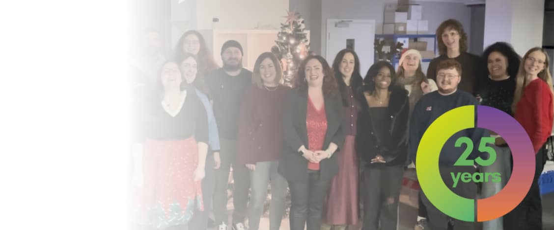 Team celebrating 25 years anniversary near Christmas tree