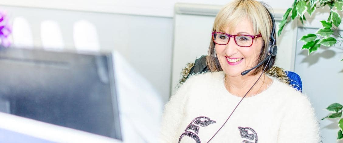 Smiling woman wearing headset at computer desk