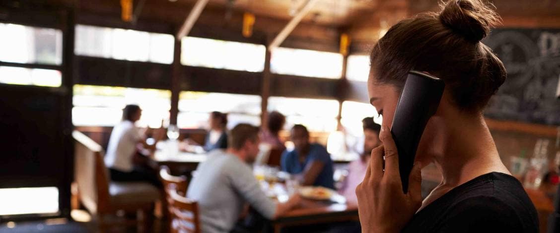 Woman talking on phone in busy restaurant