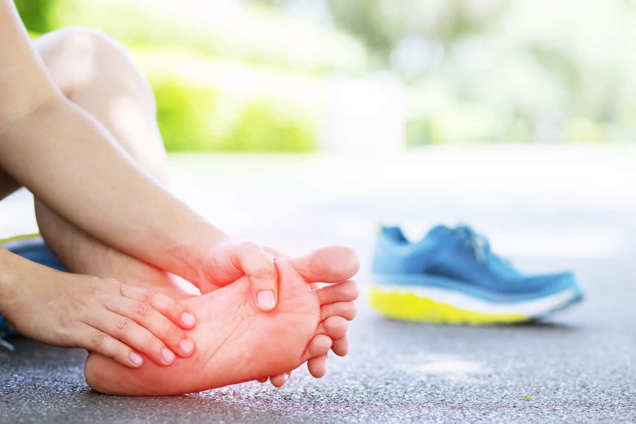 Runner with peripheral neuropathy in feet touching their foot