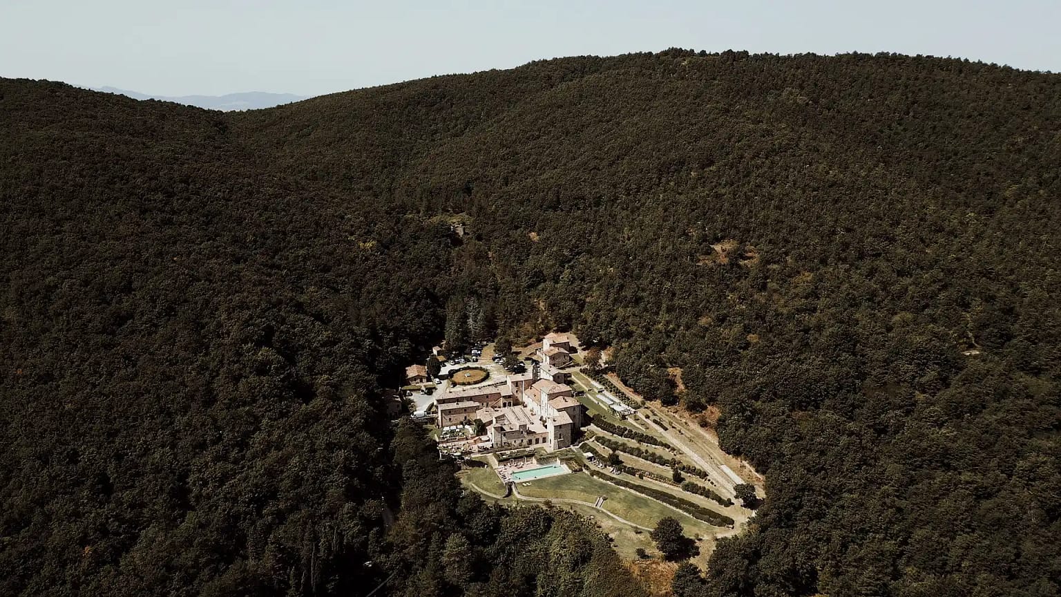 Aerial view of rustic village in forested hills.