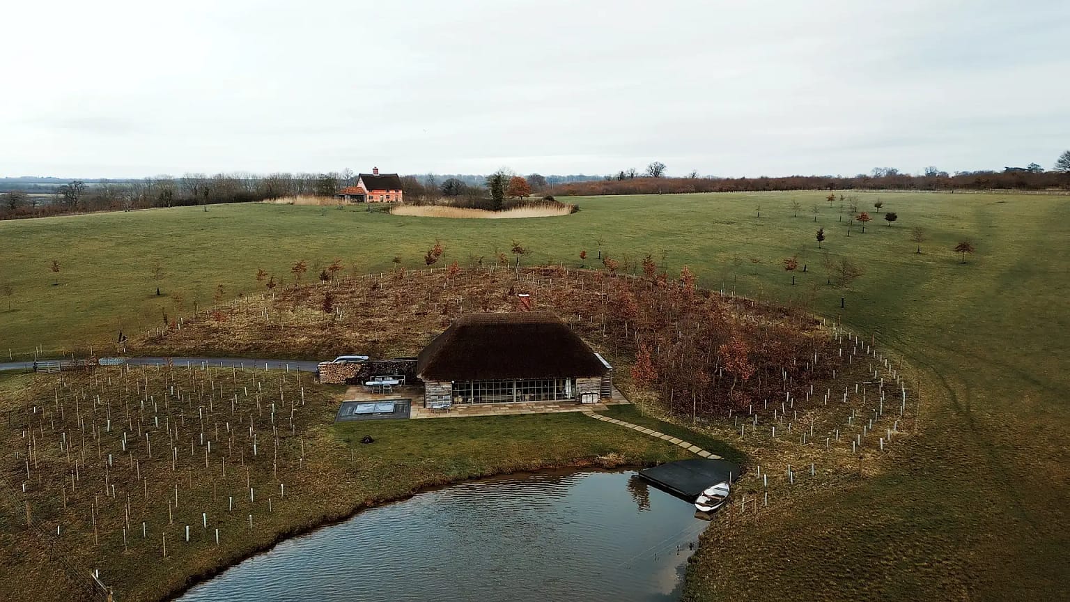 Aerial view of grassy landscape, house, and pond.