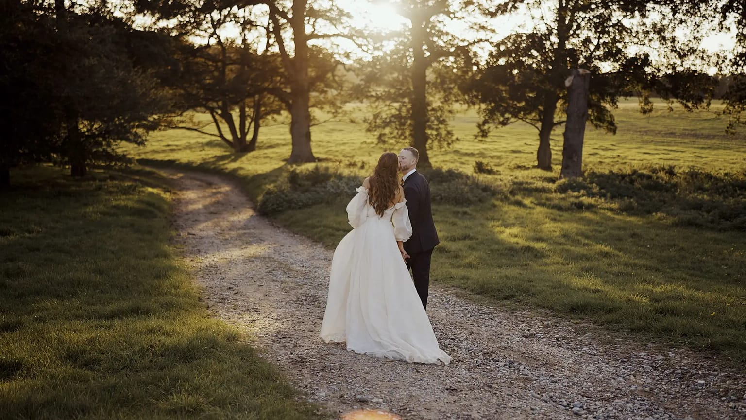 Couple walking on path, sunset in background.