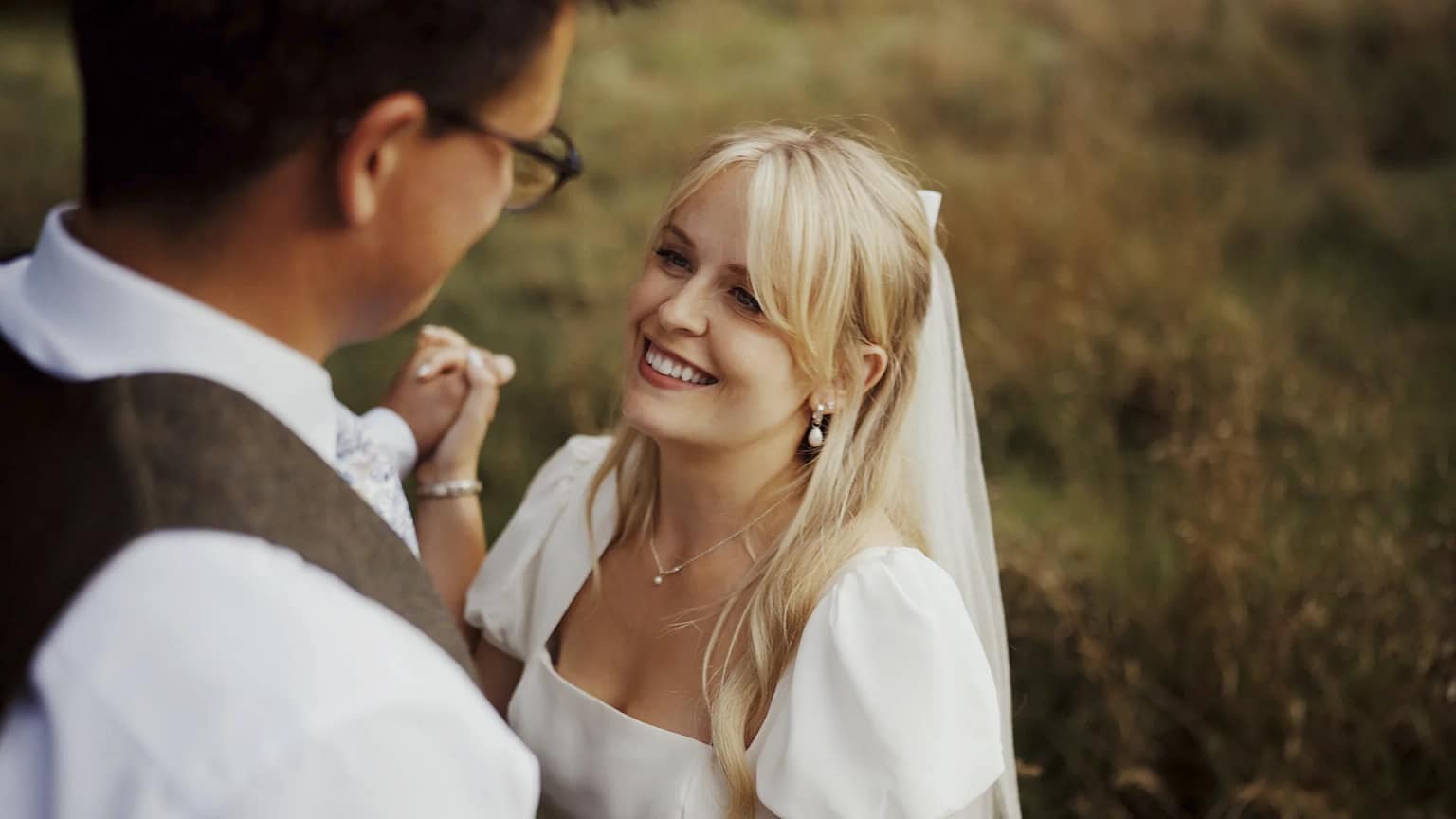 Bride and groom smiling on wedding day outdoors.