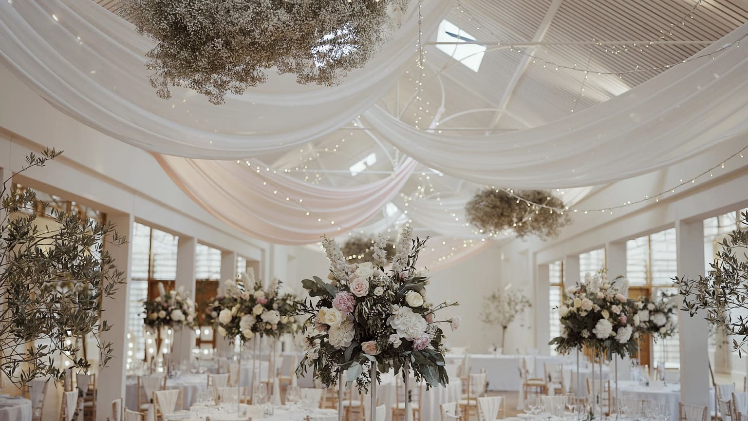 Elegant wedding reception with floral centerpieces and drapery.
