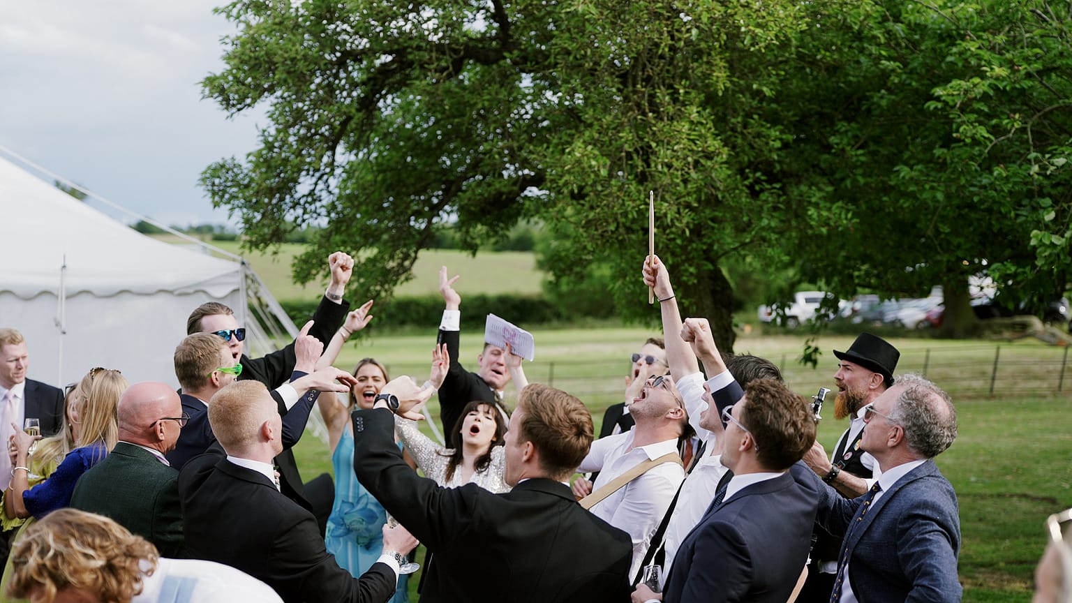 Cheerful group celebrating outdoors near a tree.