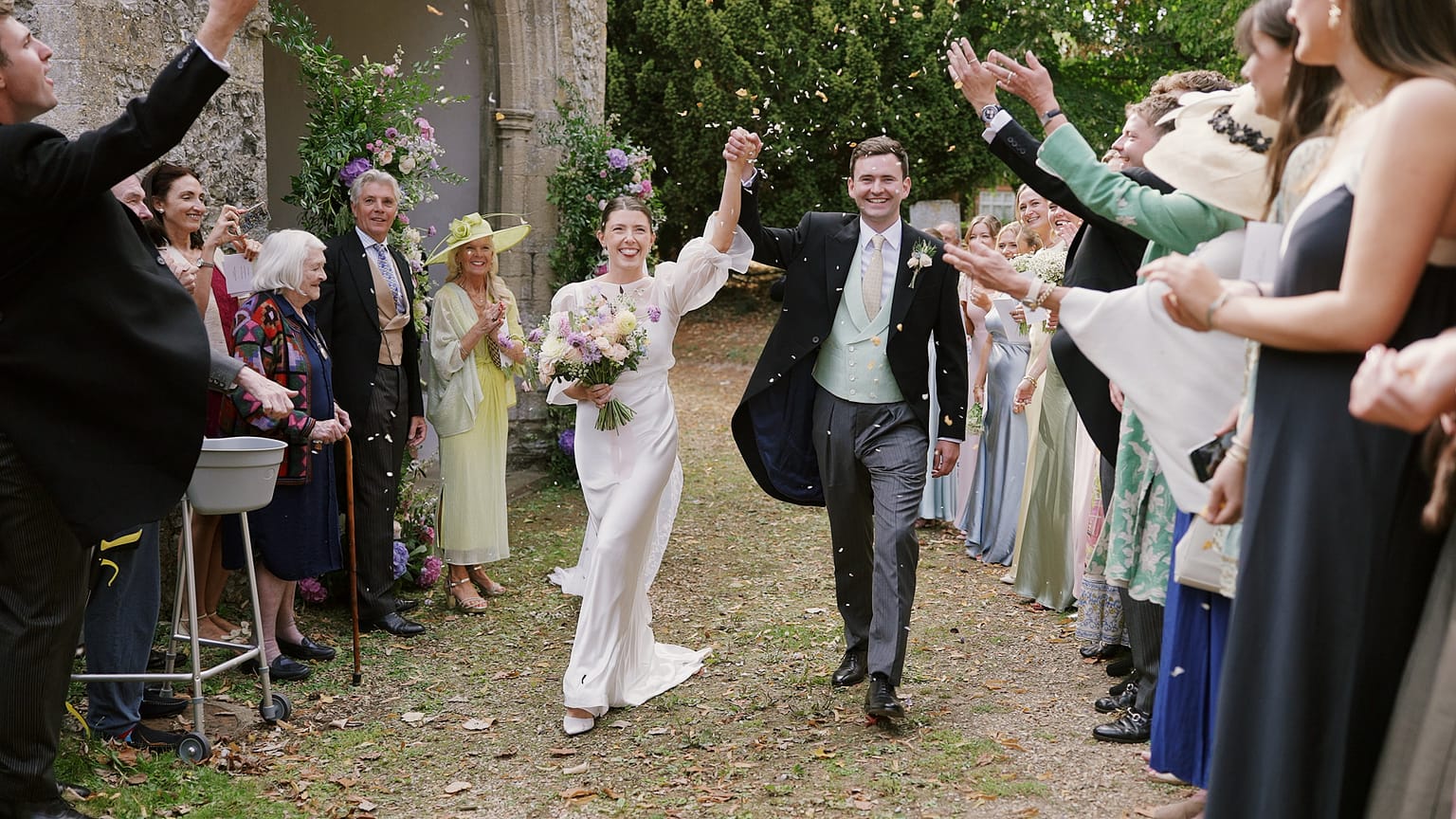 Bride and groom walking through confetti outside church