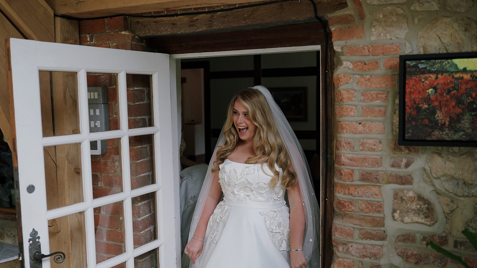 Bride in doorway smiling excitedly in wedding dress