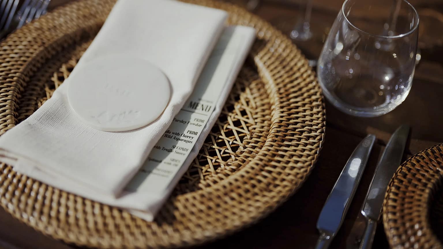 Elegant table setting with woven placemat and silverware.