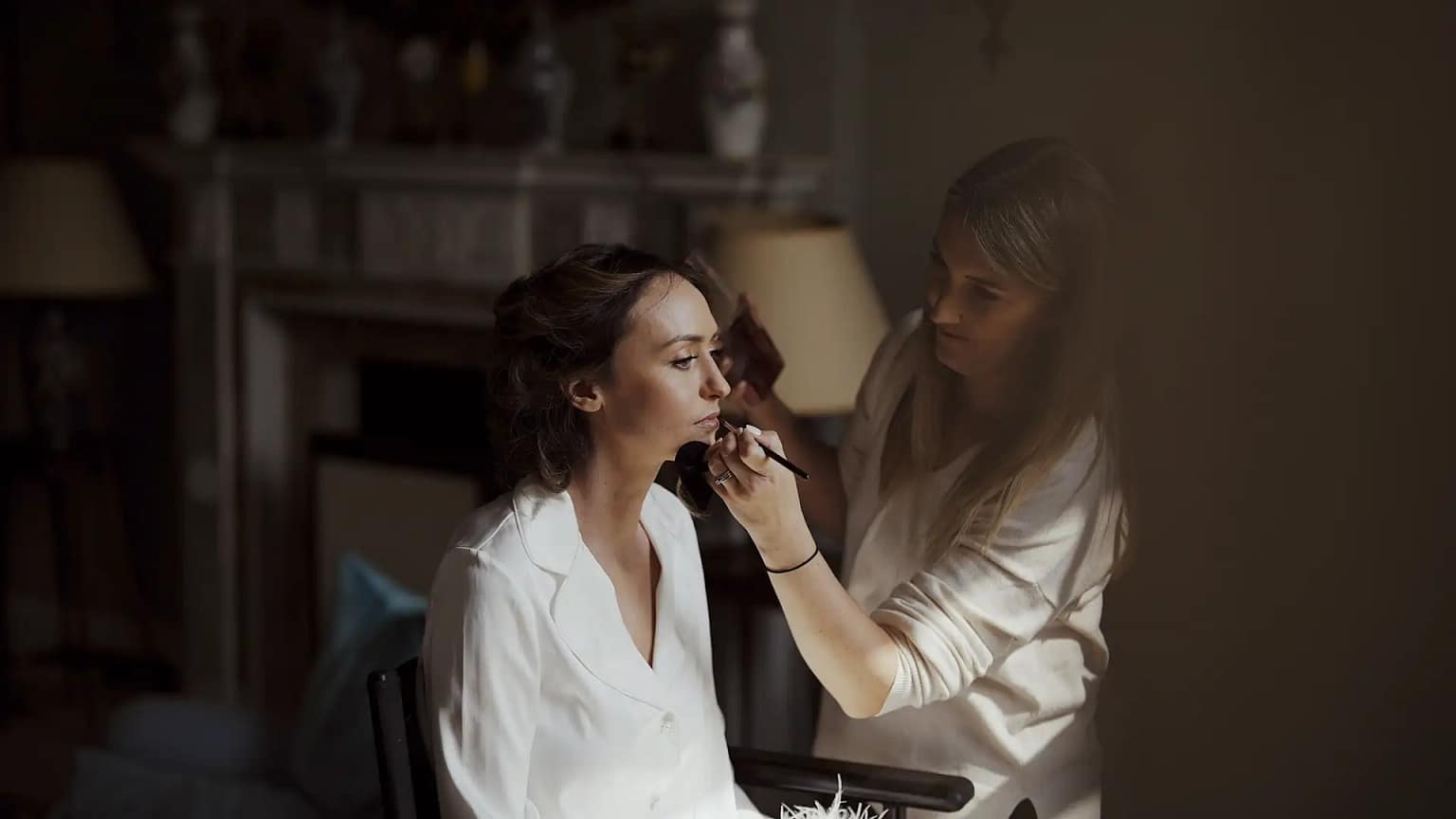 Makeup artist applies blush to woman's face.