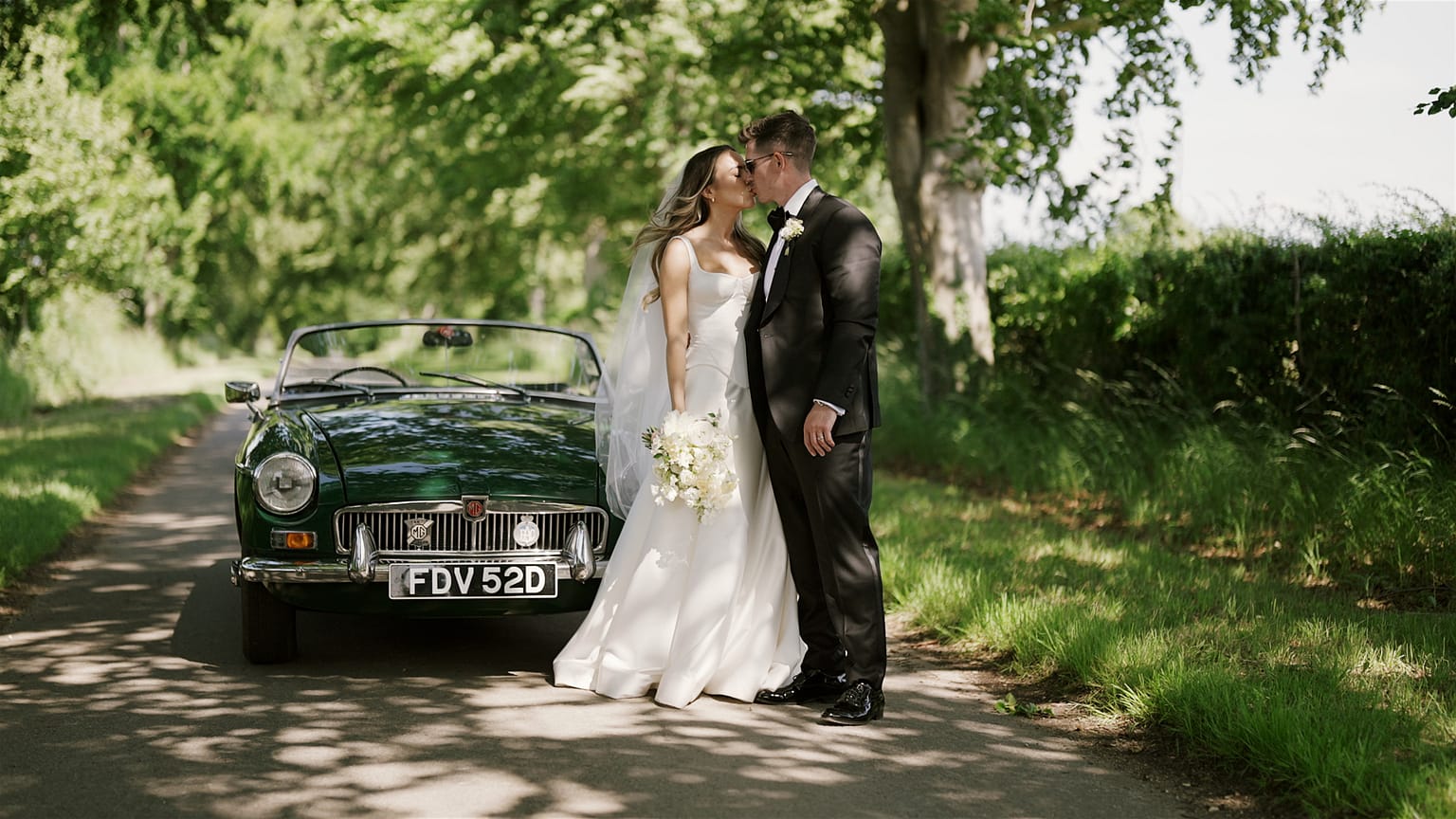 Wedding couple kissing by vintage car
