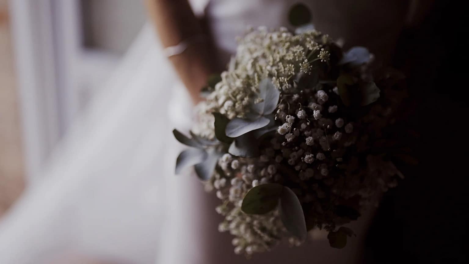 Bride holding floral bouquet in wedding dress.