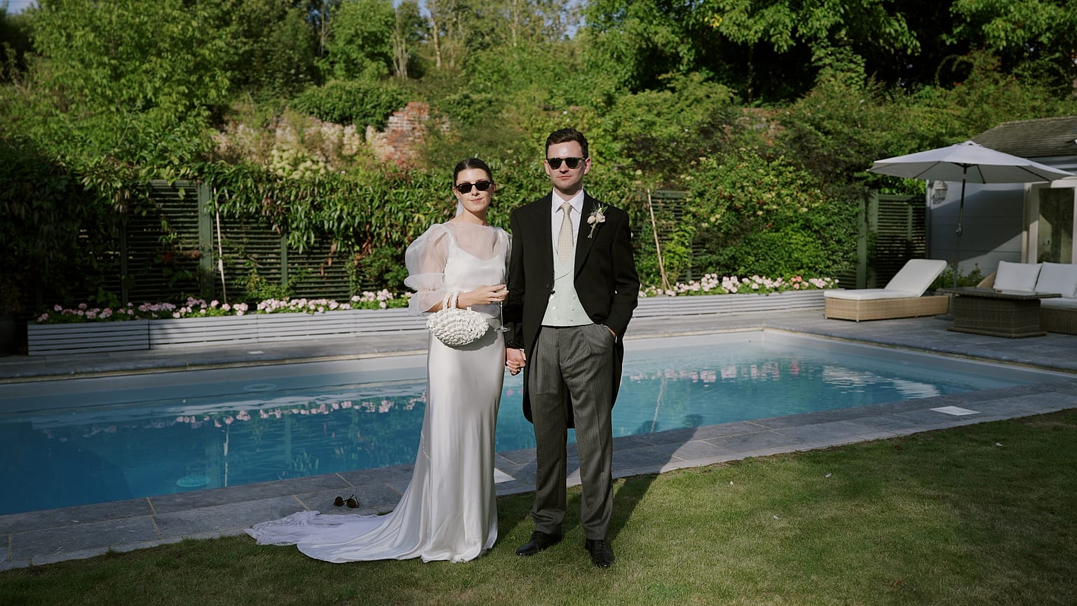 Bride and groom beside garden swimming pool