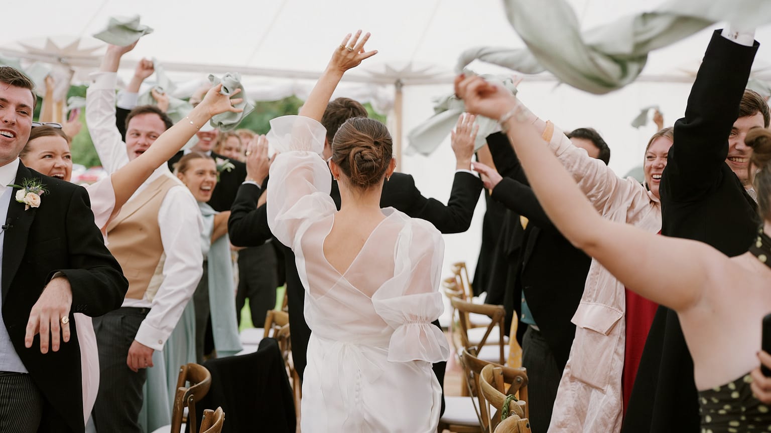 Bride entering lively wedding reception with cheering guests