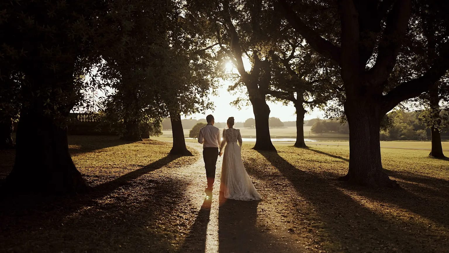 Couple walking under trees at sunset