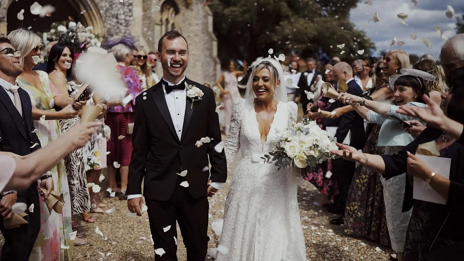 Bride and groom exiting church amid confetti celebration.