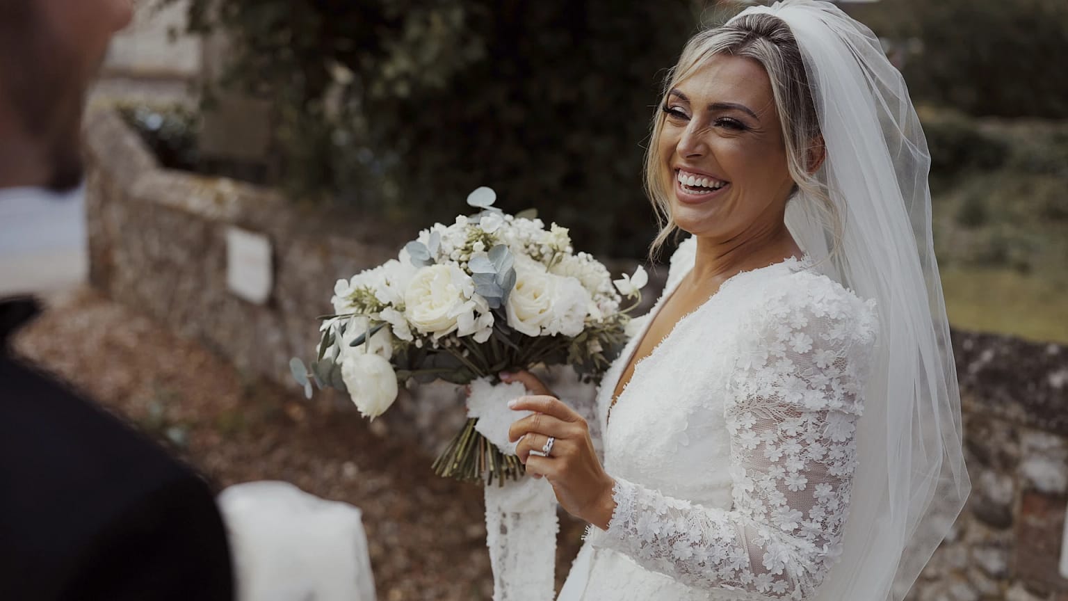 Smiling bride with bouquet at outdoor wedding