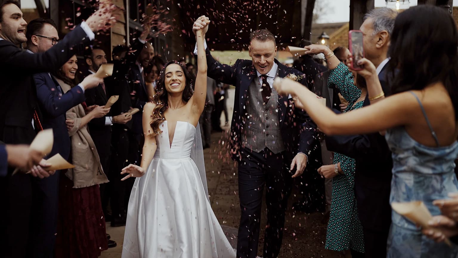 Happy couple walking through wedding confetti celebration.