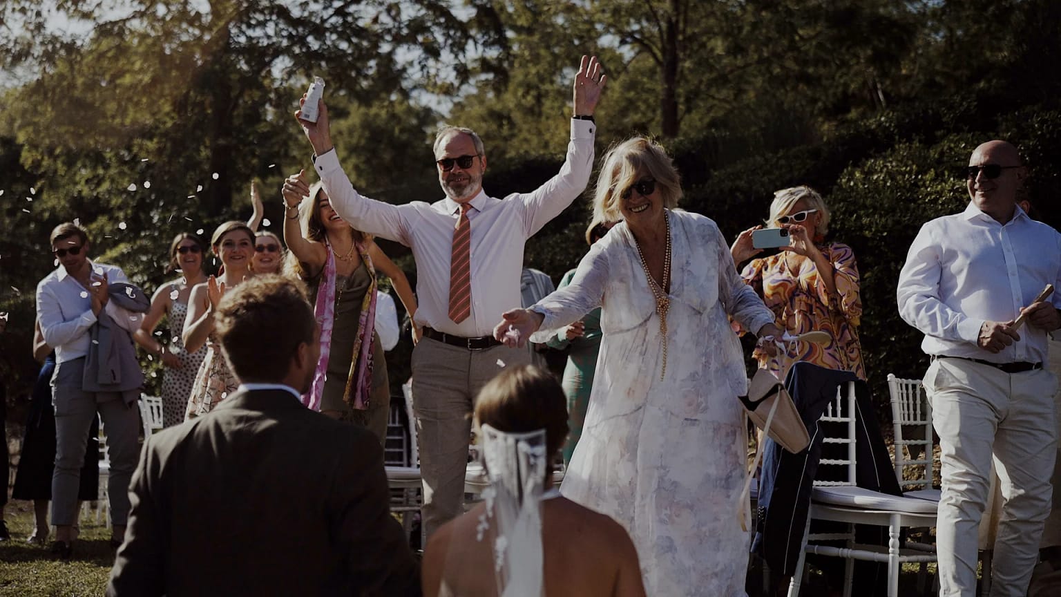 Guests celebrate at outdoor wedding ceremony.