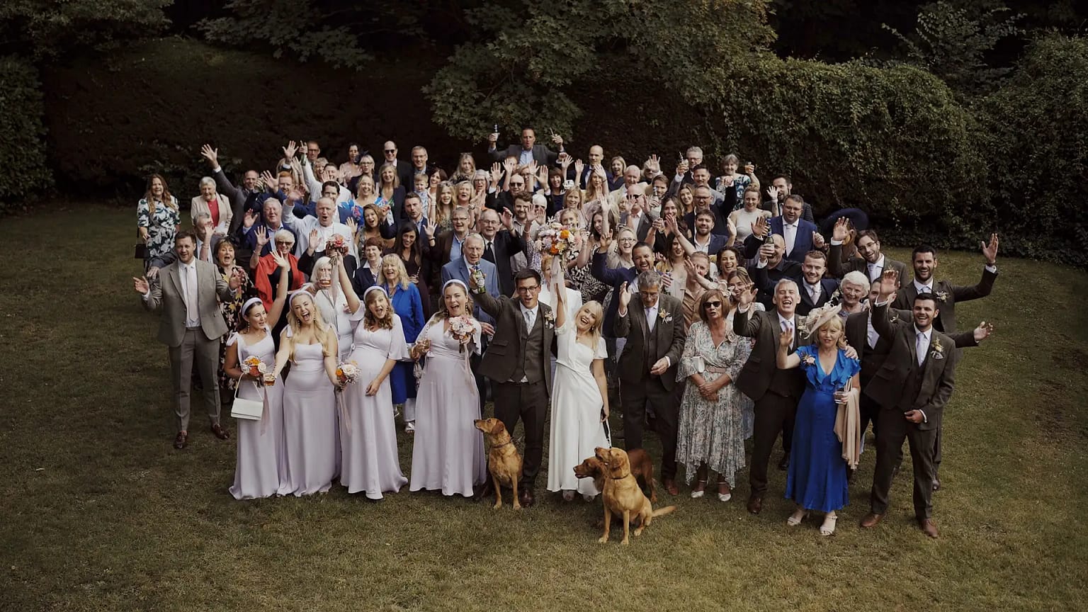 Large group celebrating at outdoor wedding event.