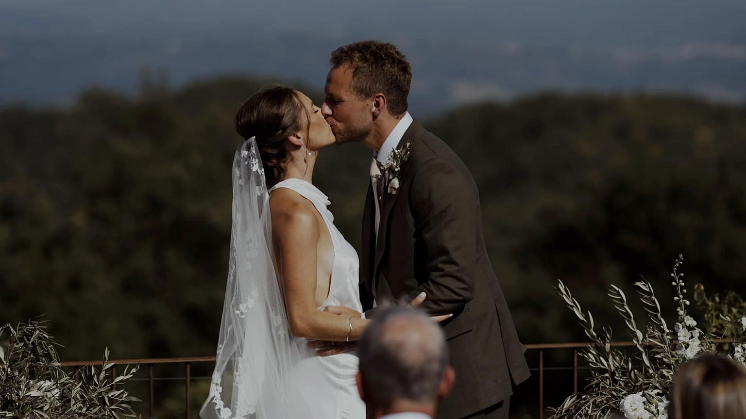 Bride and groom kiss at outdoor wedding ceremony.