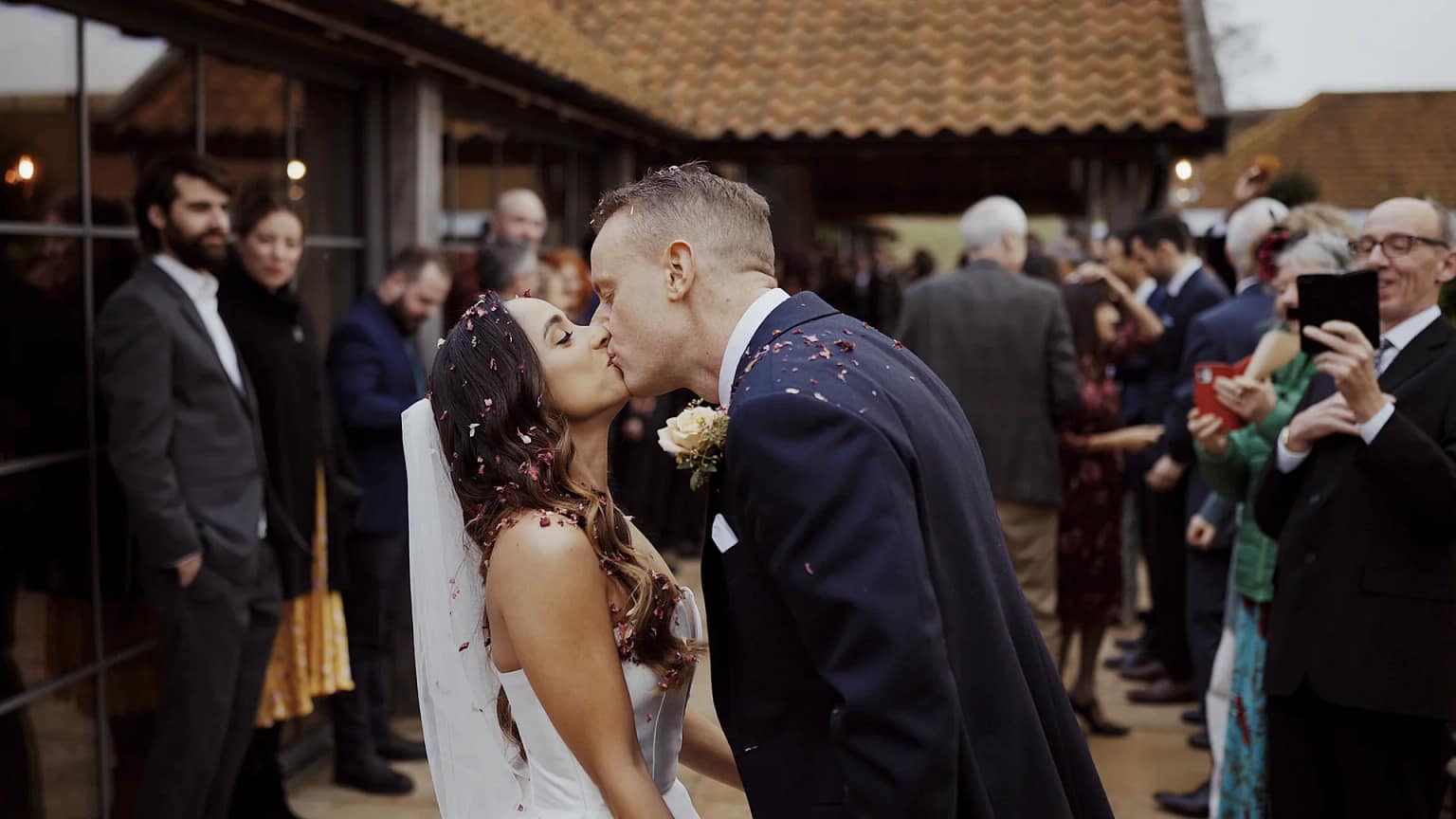 Bride and groom kissing at outdoor wedding ceremony.