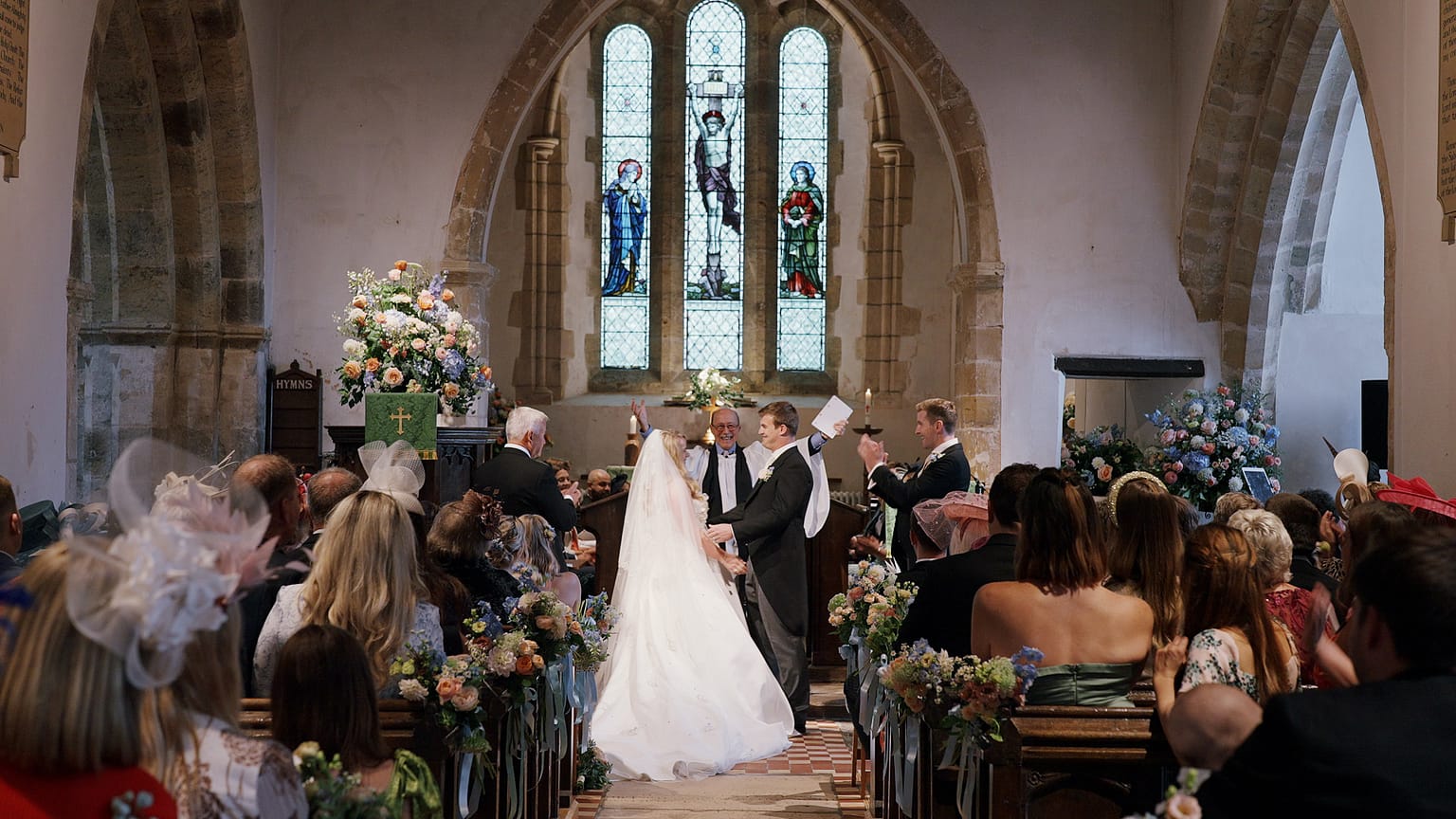 Wedding ceremony in church with guests seated.