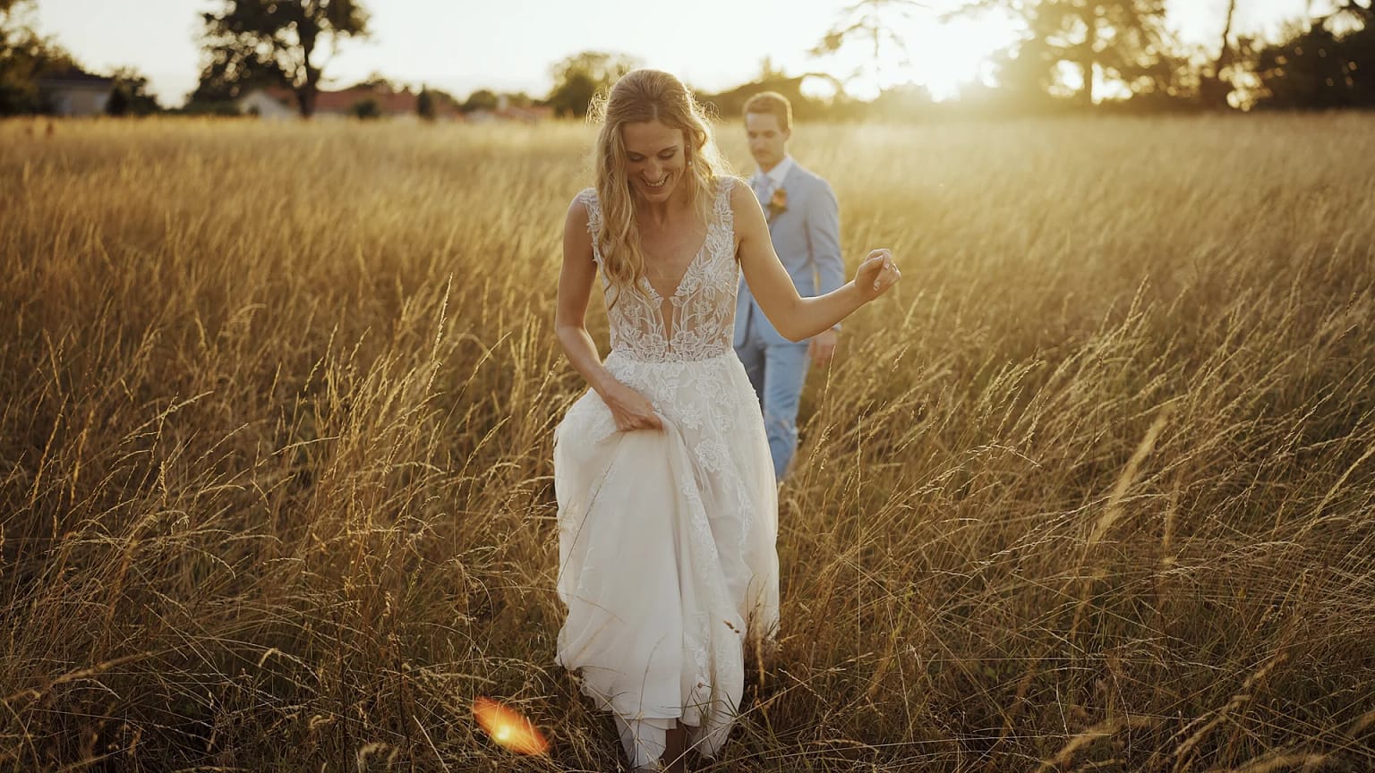 Bride and groom walking through sunny field