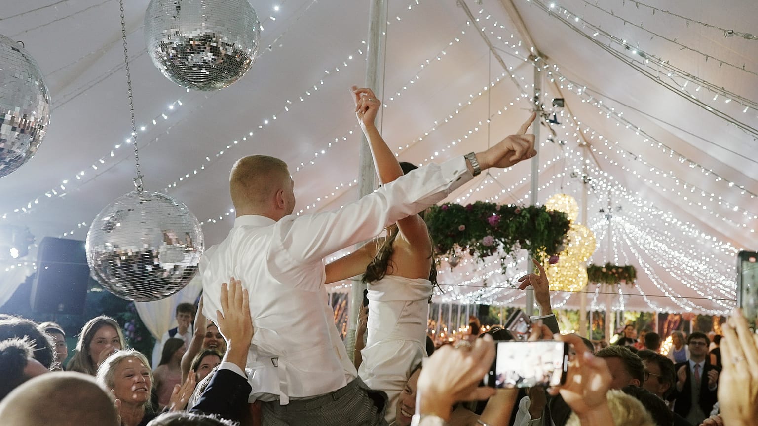 Wedding celebration with couple lifted by guests