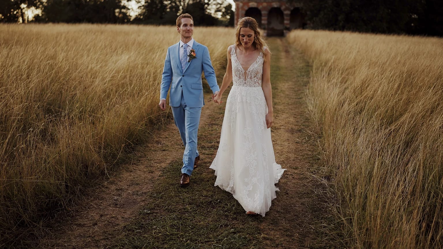 Bride and groom walking through field