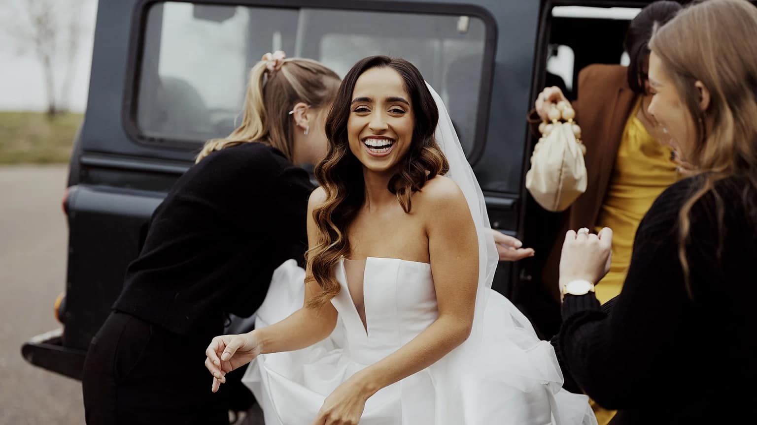 Bride smiling exiting car with friends