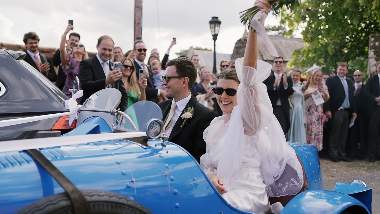 Bride and groom leaving in vintage blue car