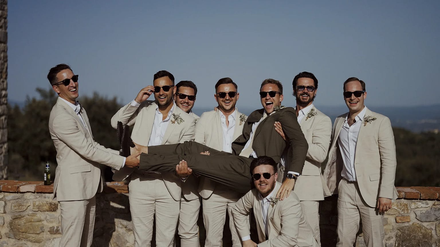Groomsmen lift groom in outdoor wedding scene