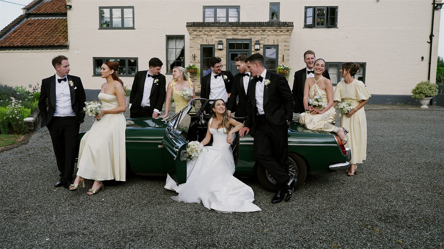 Wedding party posing by vintage car