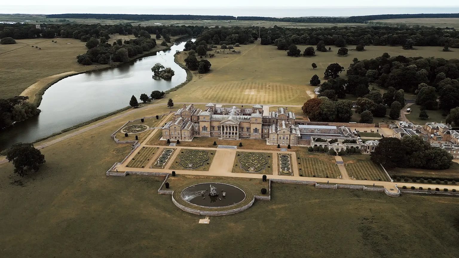 Aerial view of grand estate with gardens and river.