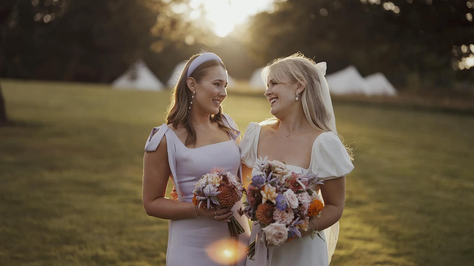 Two women smiling with bouquets in a field