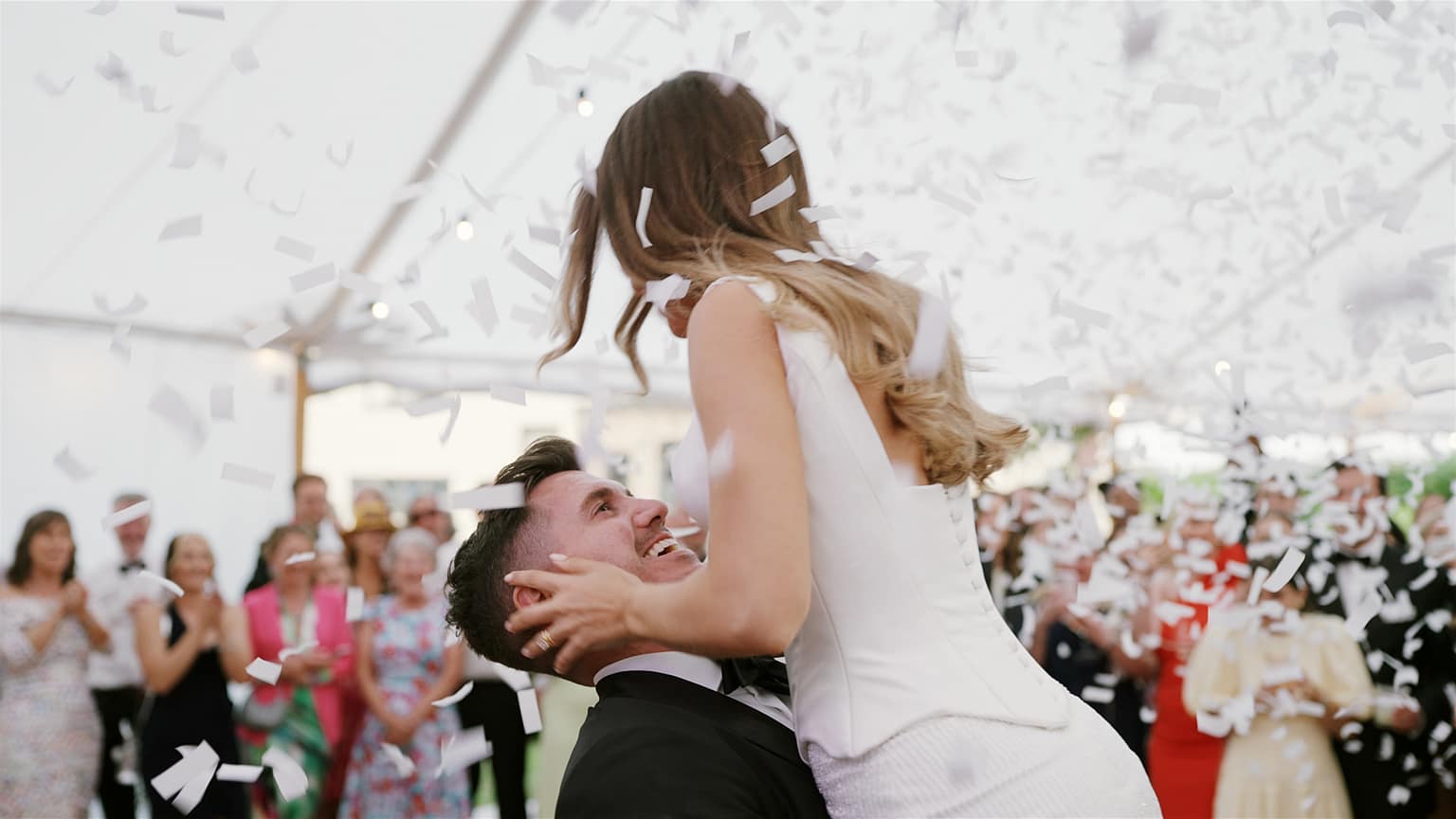 Bride and groom celebrating under confetti at wedding.