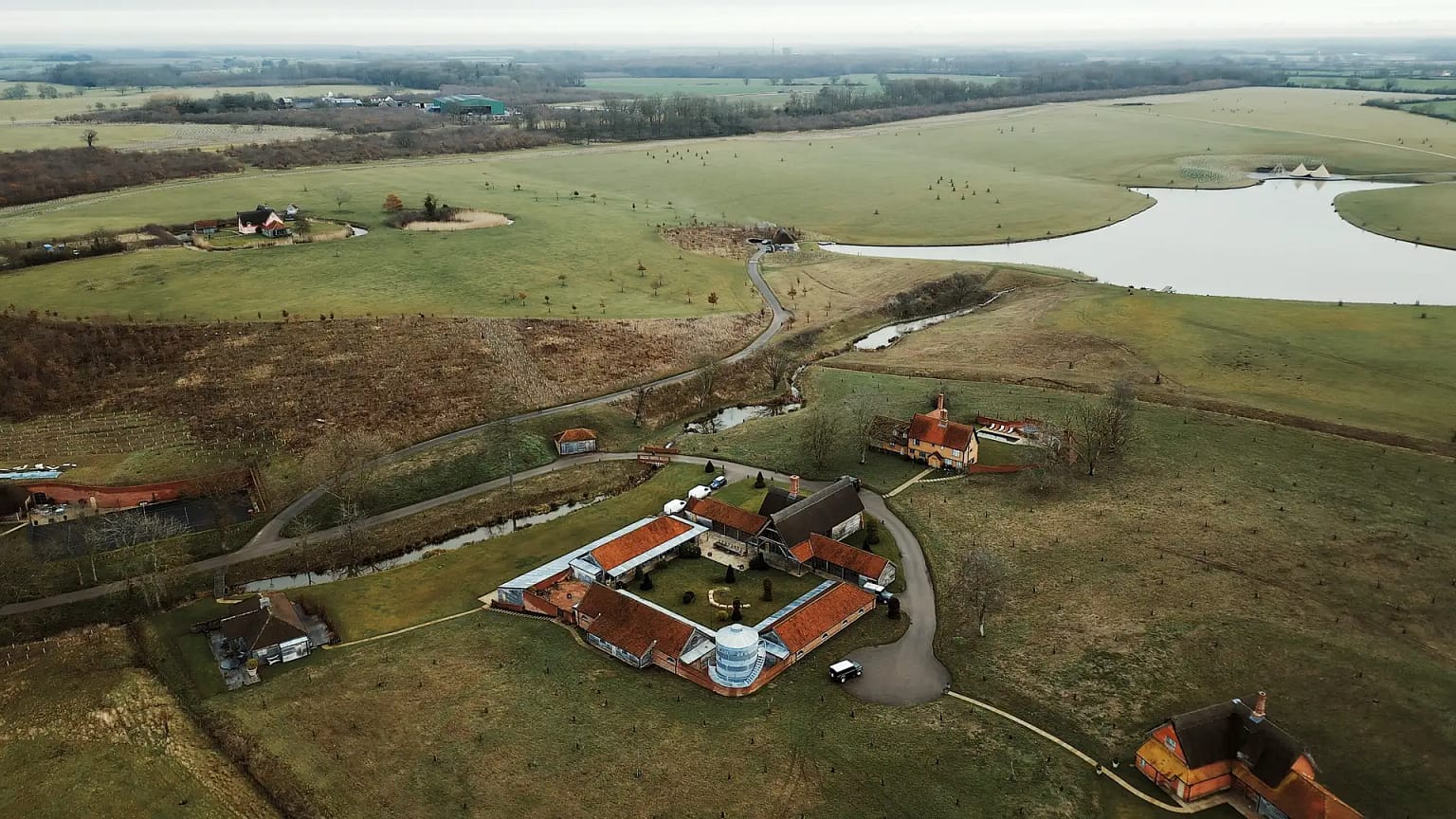 Aerial view of countryside with farmhouse and lake.