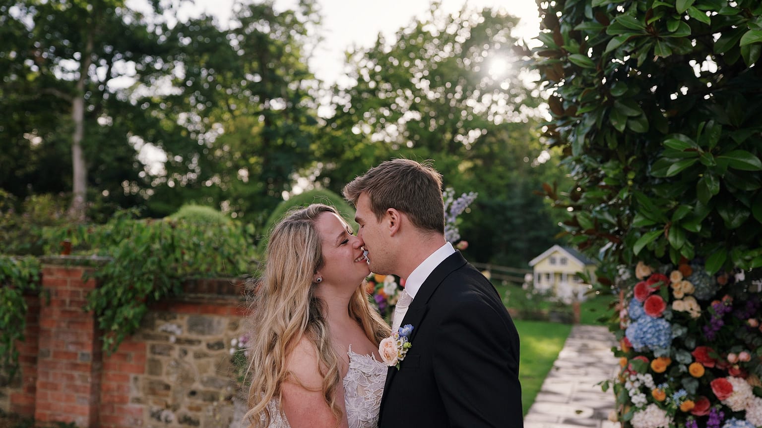 Bride and groom kissing in garden setting.