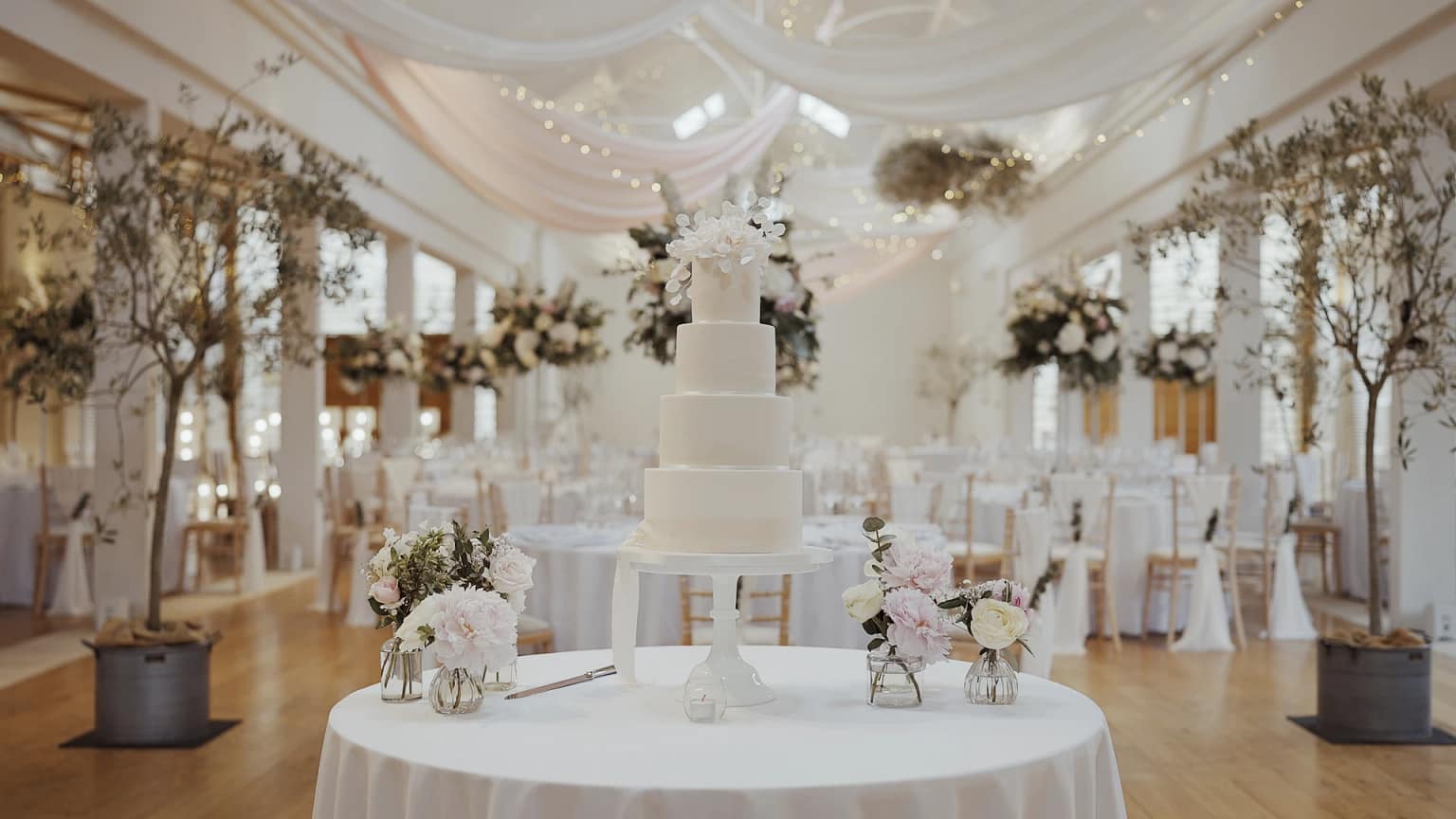 Elegant wedding hall with tiered white cake.