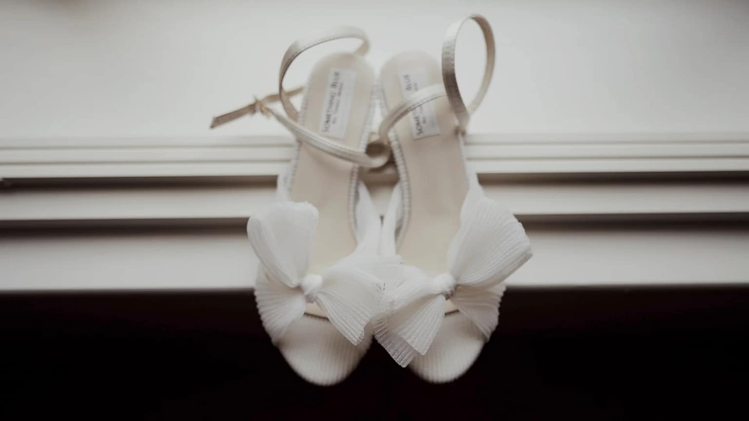 Elegant white sandals with bows on display.