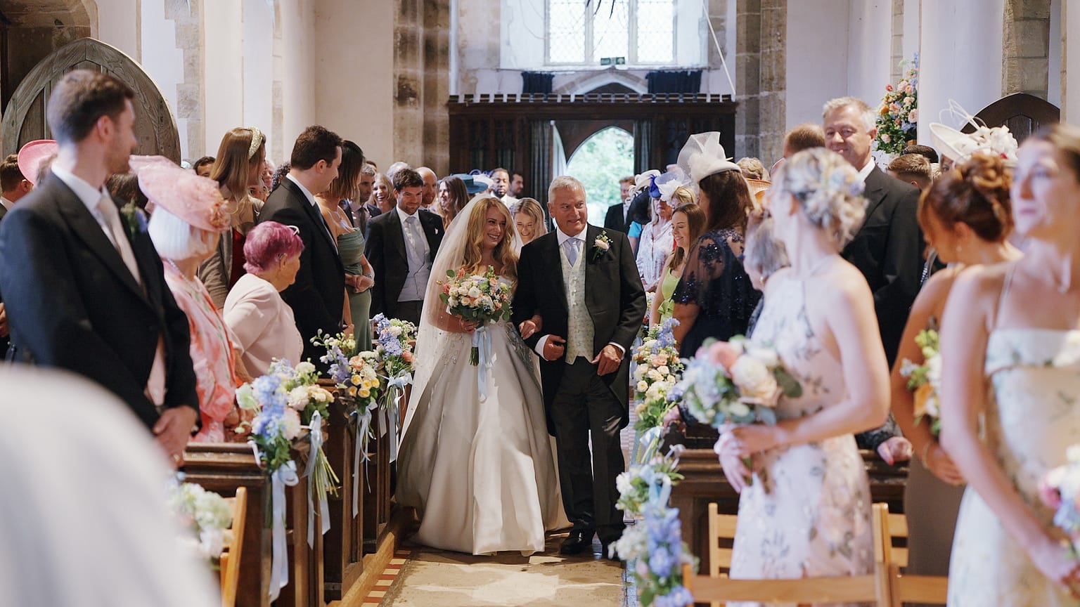 Bride walking down church aisle with father.