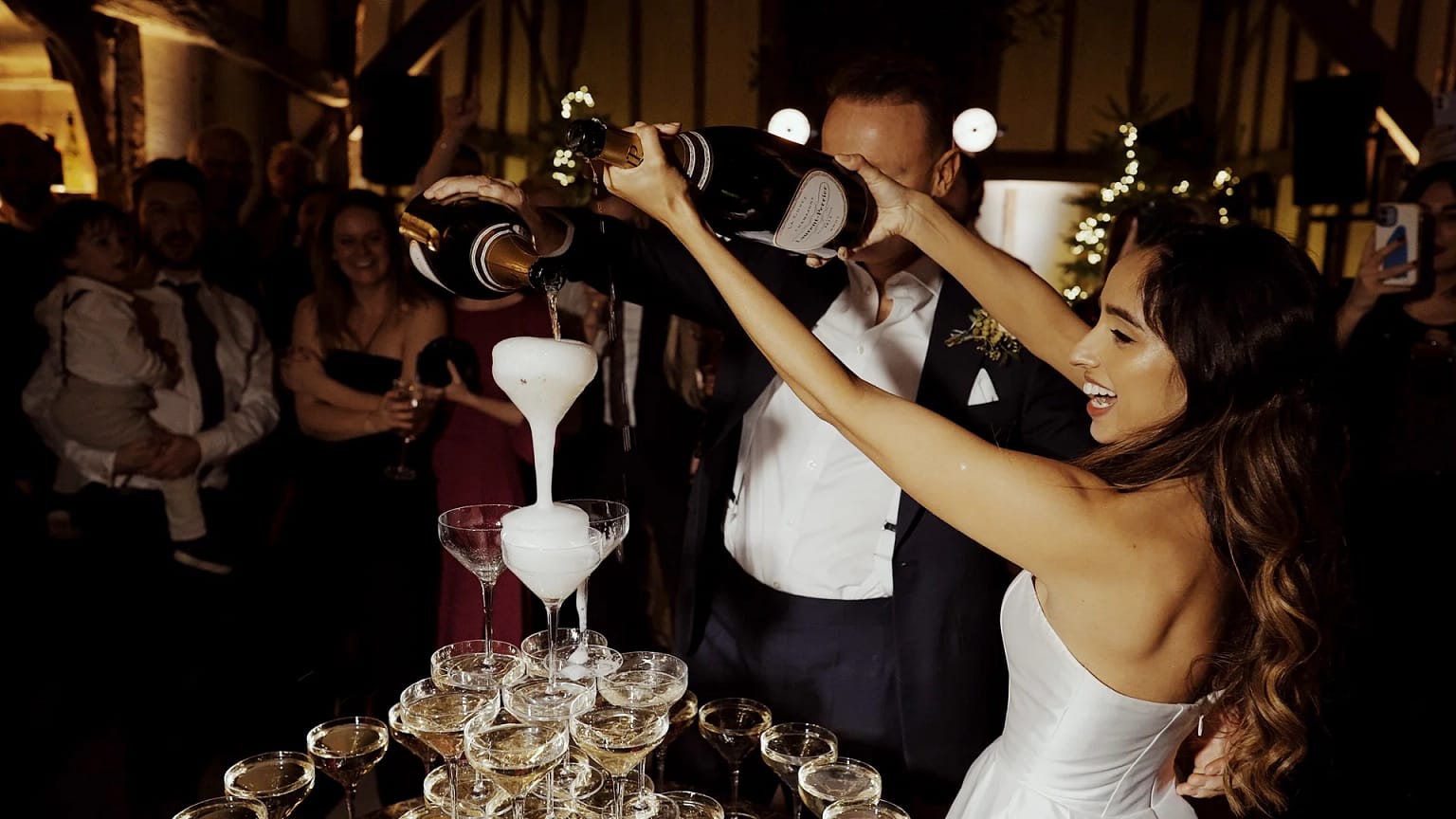 Couple pouring champagne tower at celebration