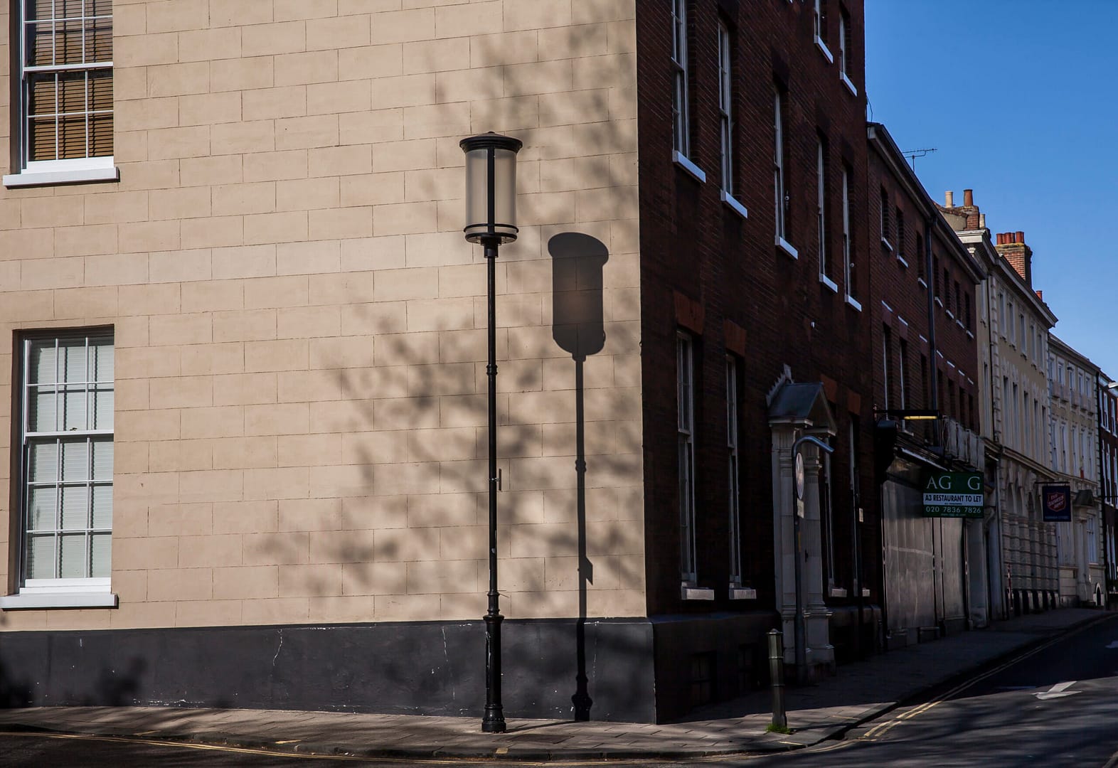 Streetlamp casting shadow on brick wall corner.